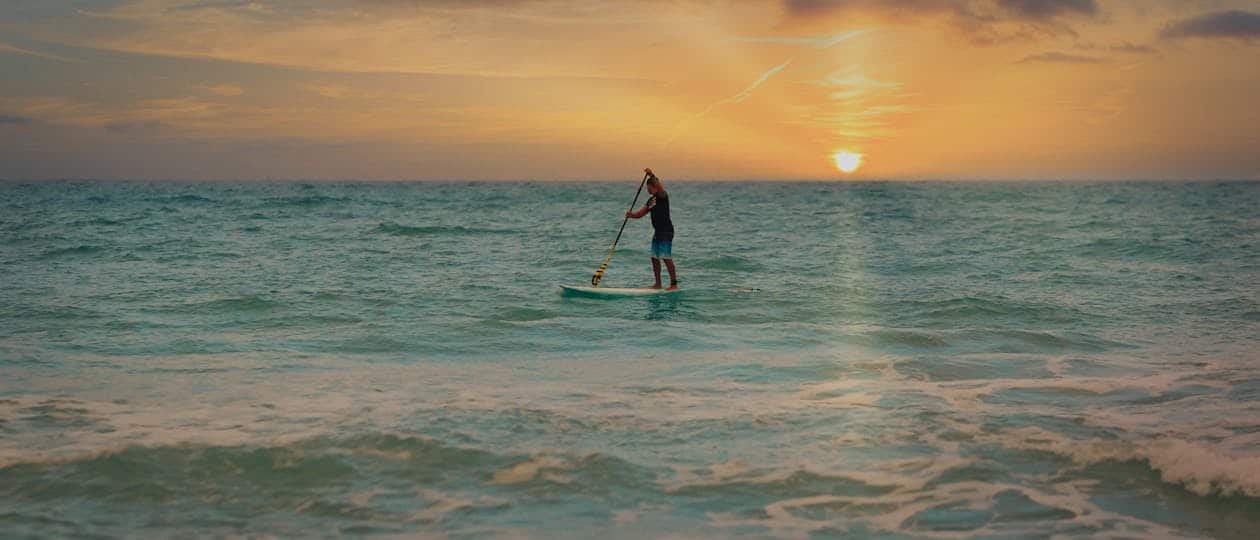 Paddleboarding on calm ocean water at sunset near Navarre Beach